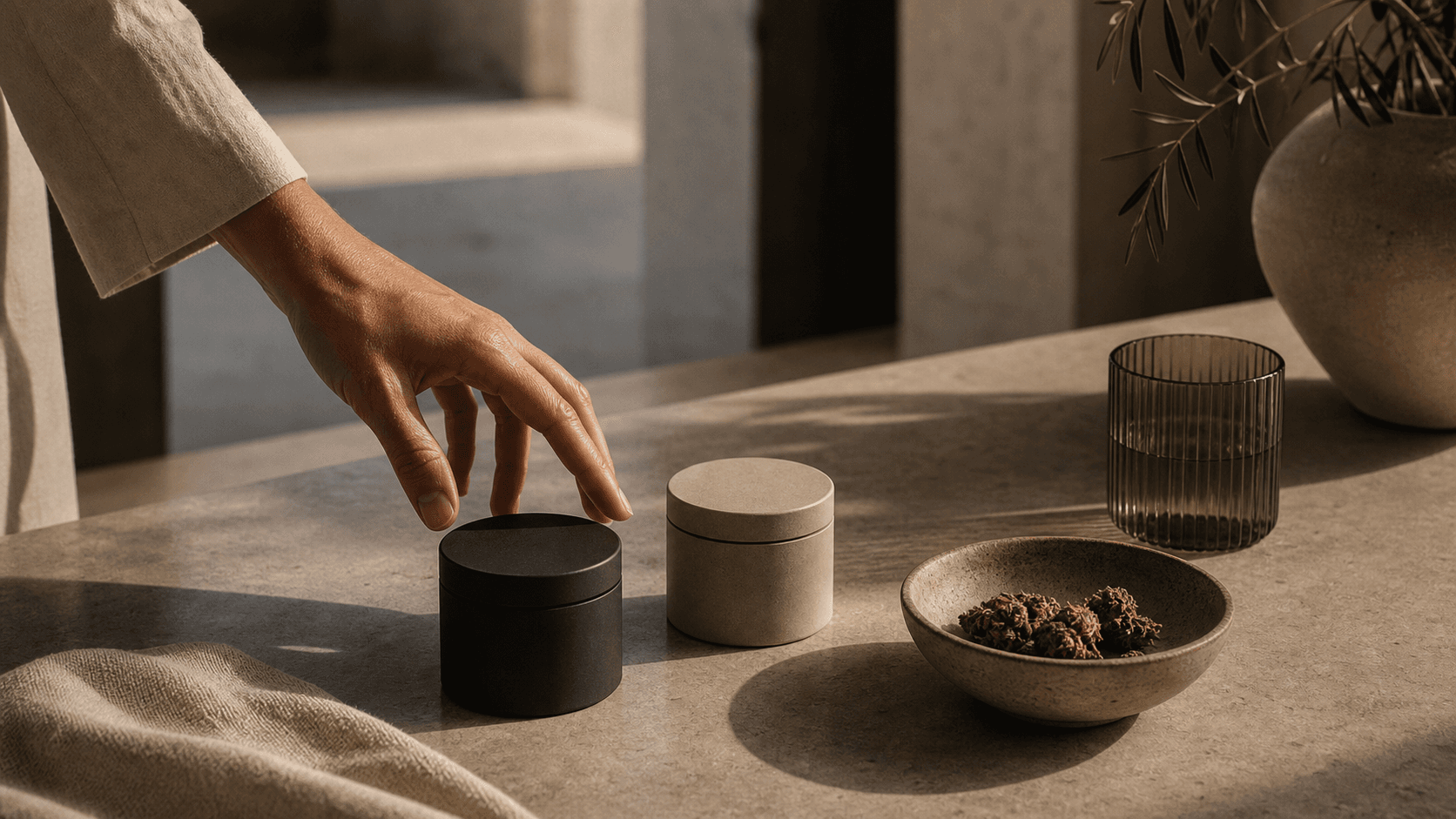 A hand choosing between two refined cannabis containers on a limestone table